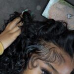 Woman with voluminous black curly hair and meticulously styled, laid edges along her hairline.