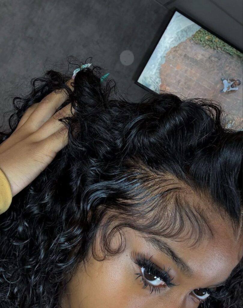 Woman with voluminous black curly hair and meticulously styled, laid edges along her hairline.