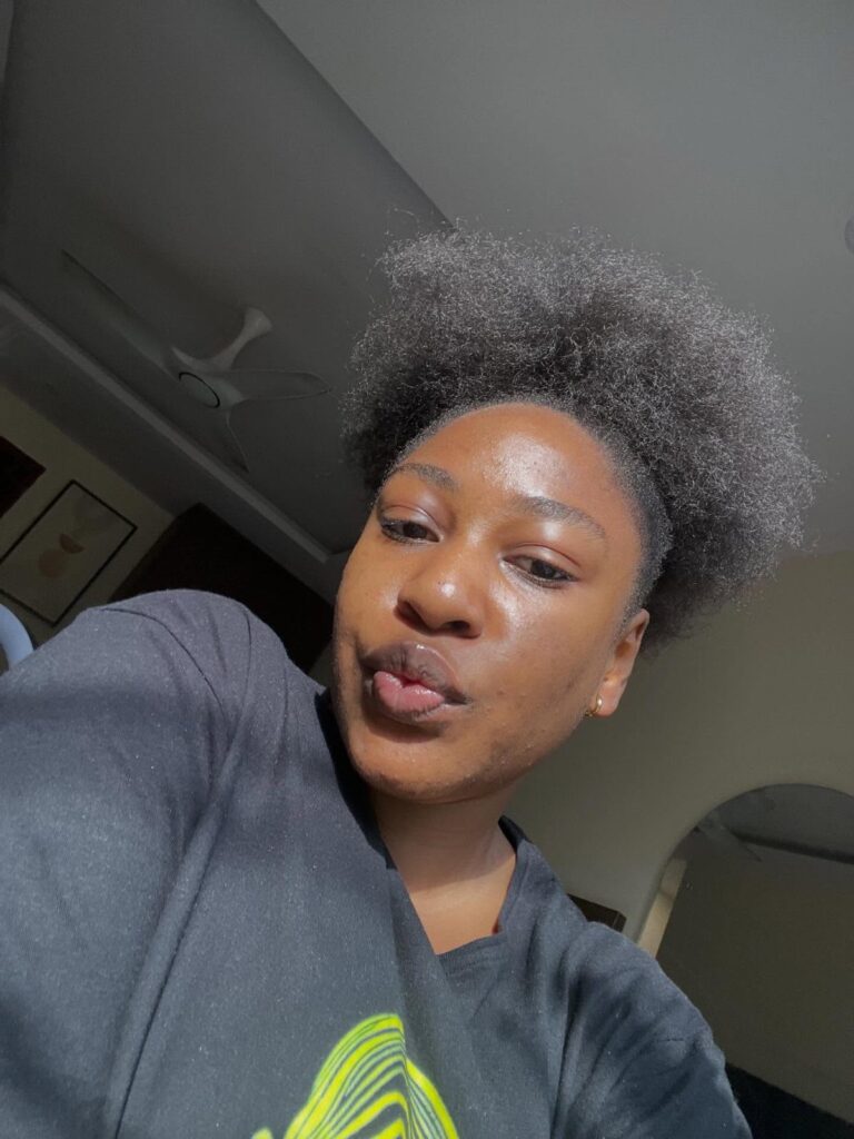 Black woman with a large natural afro hairstyle wearing a black t-shirt.