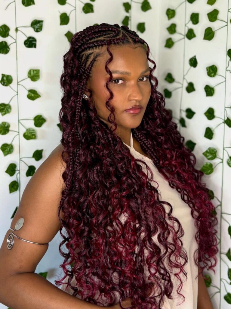 Woman with long burgundy-red Fulani braids and curly ends against ivy background