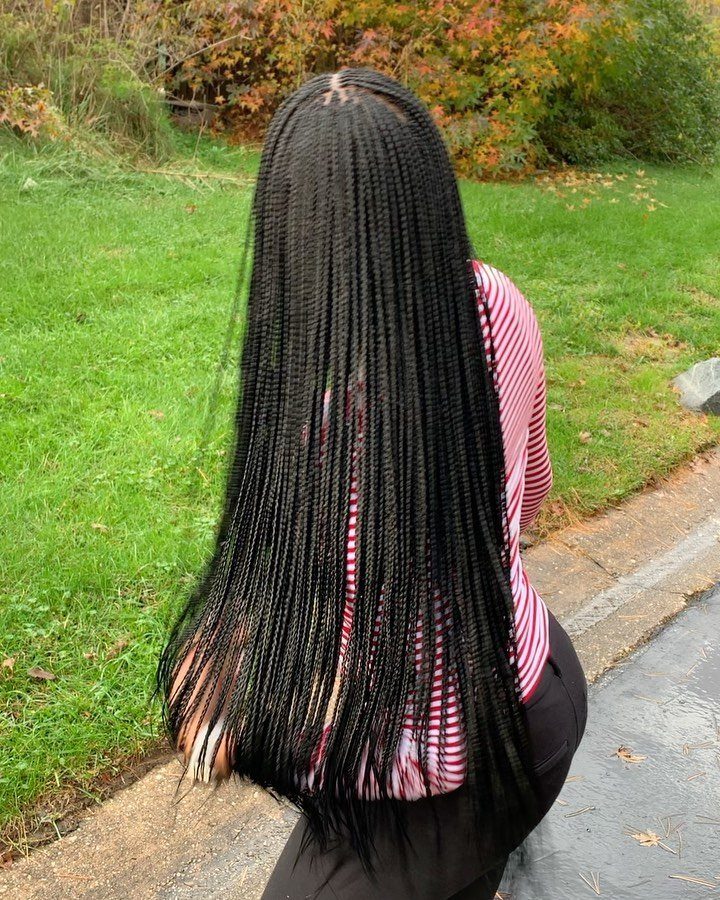 Long black box braids on a person wearing a red striped shirt outdoors.