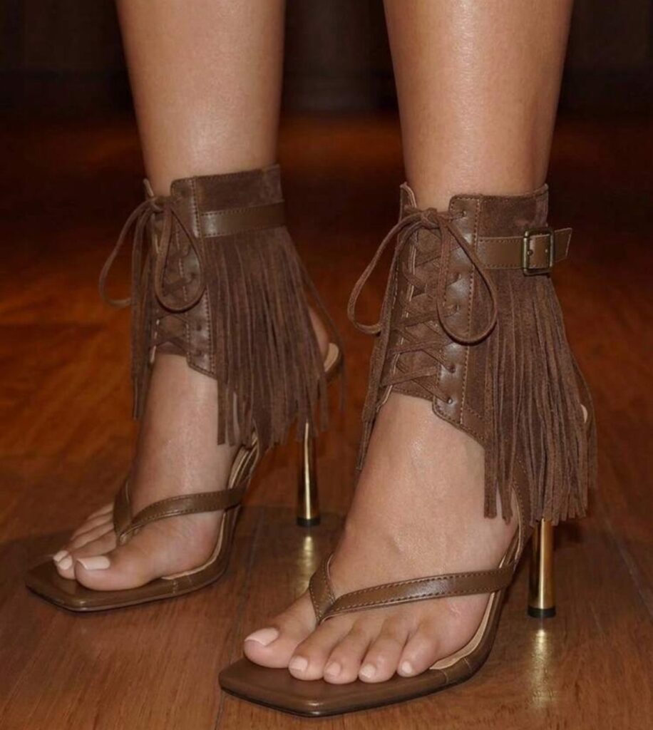Brown leather fringe high heels with lace-up ankle straps on a wooden floor