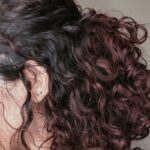 Curly hair dyed in deep chocolate brown and plum purple tones.