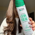 Not Your Mother's Clean Freak Dry Shampoo held in front of long brown hair.