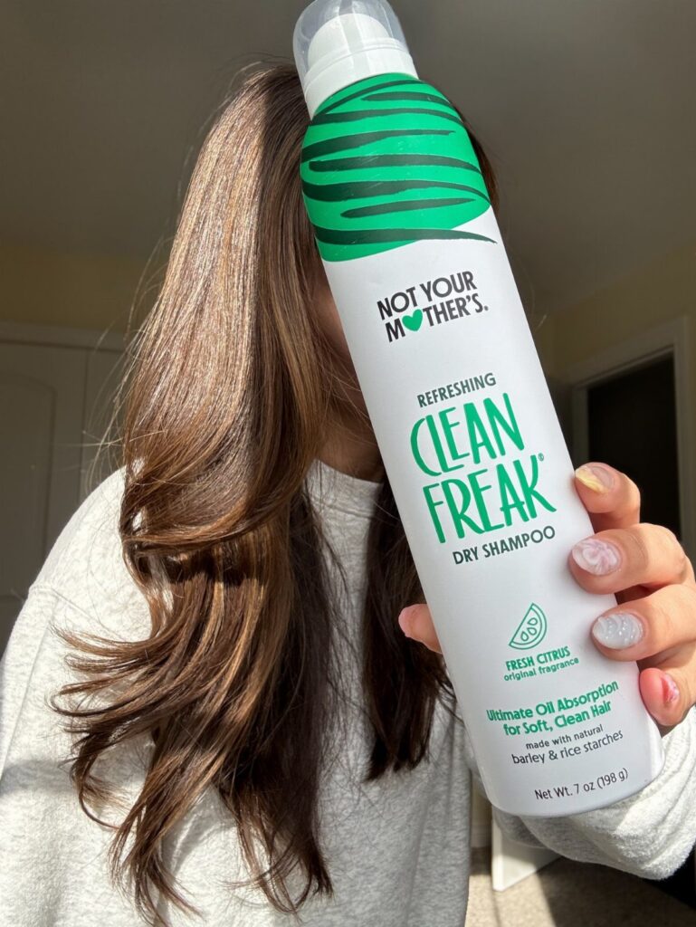 Not Your Mother's Clean Freak Dry Shampoo held in front of long brown hair.