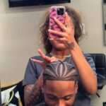Man with intricate cornrow braids and a fade haircut in a salon setting.