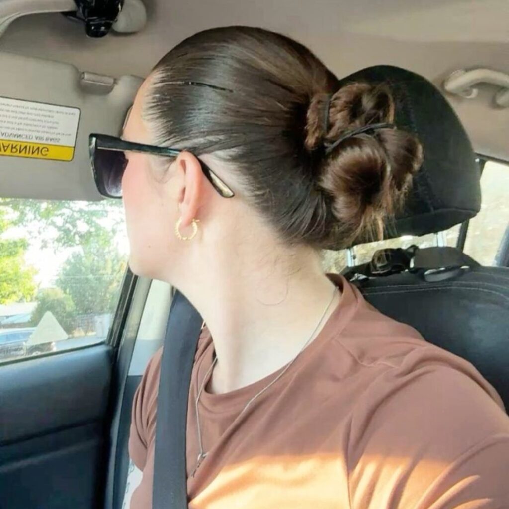 Woman with brown hair styled in a low nape knot bun inside a car