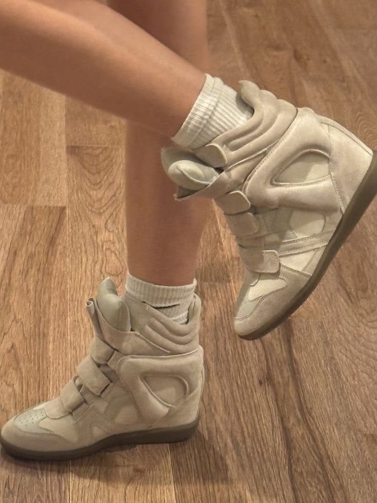Beige high top trainers with straps and white socks on wooden flooring