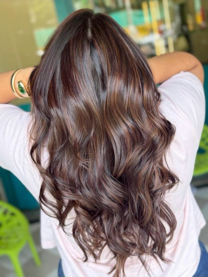 Long wavy dark brown hair with subtle balayage highlights seen from behind.