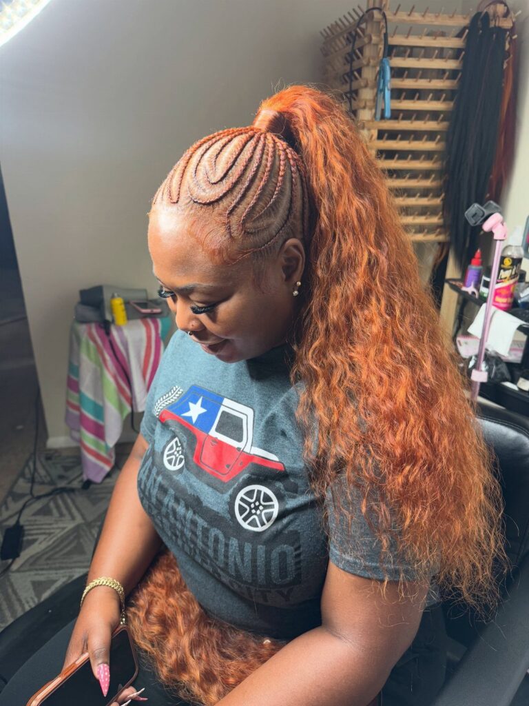 Woman with reddish-brown hair in a high ponytail with cornrow braids on top.
