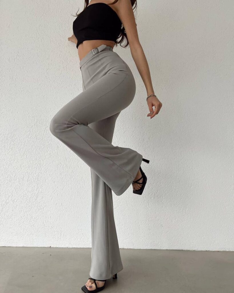 Person wearing high-waisted grey flared trousers and a black tube top posing.