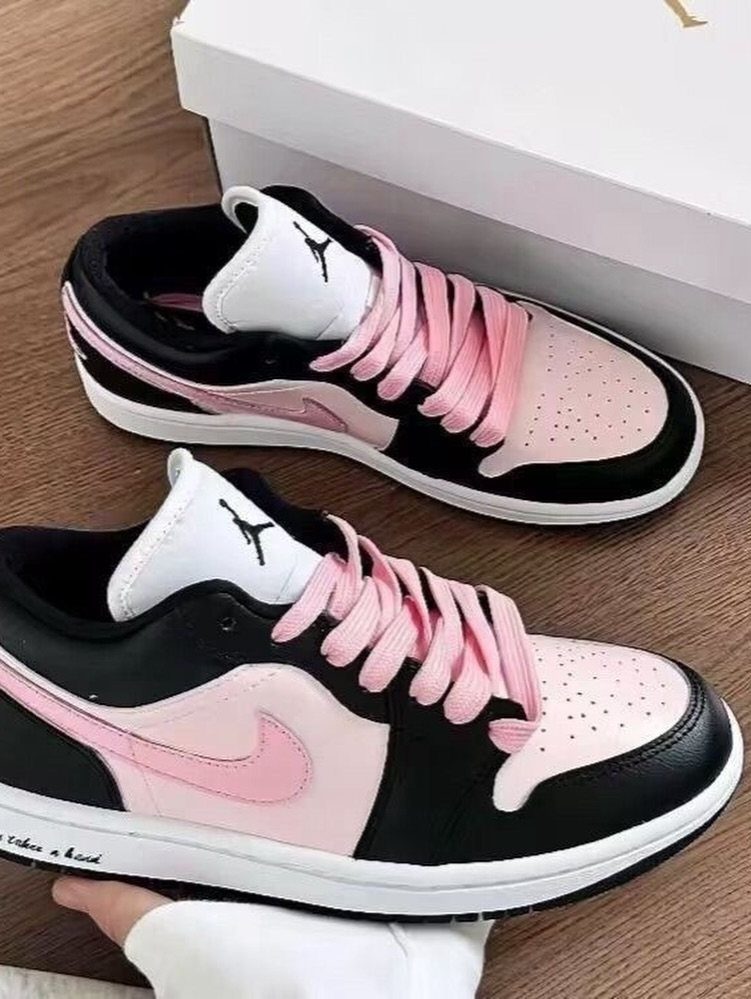 Black and pink sneakers with pink laces next to a white shoebox.